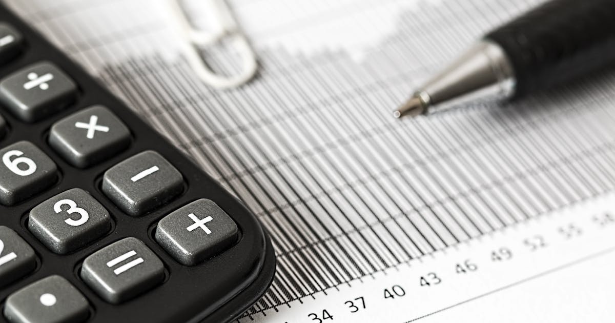 Calculadora com planilha e caneta representando simulações de investimentos