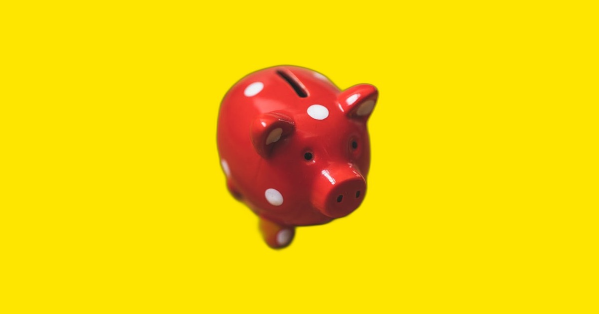 Cofrinho vermelho sobre fundo amarelo neon representando reserva de emergência