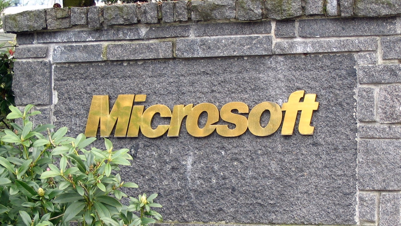 Placa com o logotipo dourado da Microsoft em um muro de pedra na sede da empresa