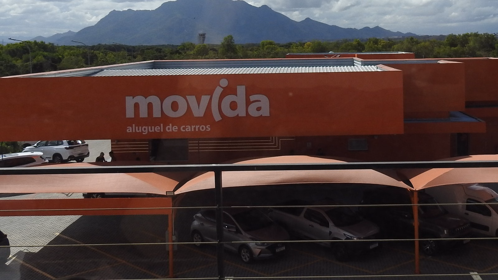 Loja da Movida aluguel de carros com o logo laranja na fachada e carros no estacionamento