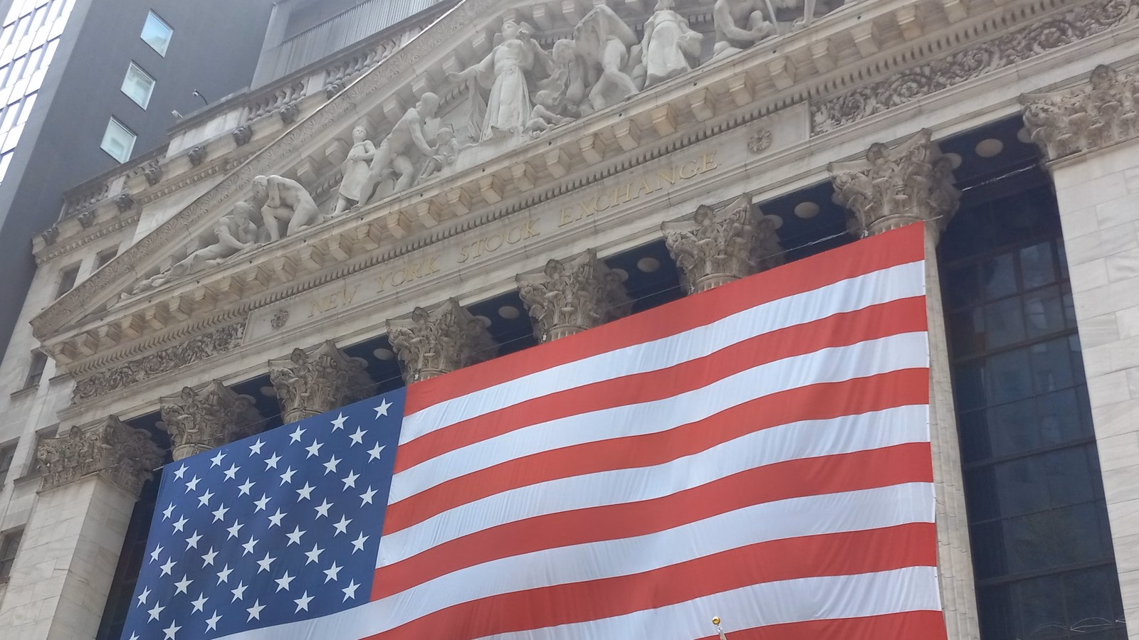 Fachada da Bolsa de Nova York com a bandeira dos Estados Unidos